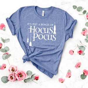 May include: A blue t-shirt with the text "It's just a bunch of Hocus Pocus" in white. The text is stylized with a broom and a cauldron.