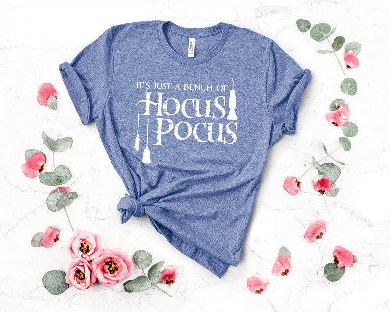 May include: A blue t-shirt with the text "It's just a bunch of Hocus Pocus" in white. The text is stylized with a broom and a cauldron.