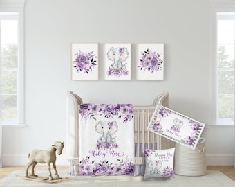 May include: A nursery set featuring a crib, bedding, and wall art with a floral and elephant theme. The set includes a crib blanket, bumper, and pillow with purple floral accents. Three framed prints depict floral arrangements and an elephant.