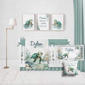 May include: A nursery set featuring a white crib with a seafoam green skirt and matching bedding. The set includes a blanket, pillow, and three framed prints with turtle illustrations. The prints and bedding have the name "Dylan James". The text "Dream as BIG as the OCEAN" is also visible.