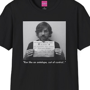 May include: Black t-shirt featuring a black and white image of a person holding a sign with text. The sign reads "WHITEHALL POLICE DEPT." and "Run like an antelope, out of control."