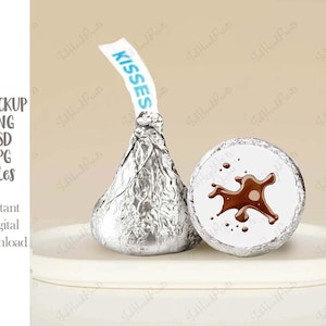 Może przedstawiać: Srebrny, owinięty w folię, czekoladowy pocałunek z białą etykietą z napisem "KISSES" oraz czekoladowy pocałunek w białym opakowaniu z brązowym wzorem rozpryskującej się czekolady.