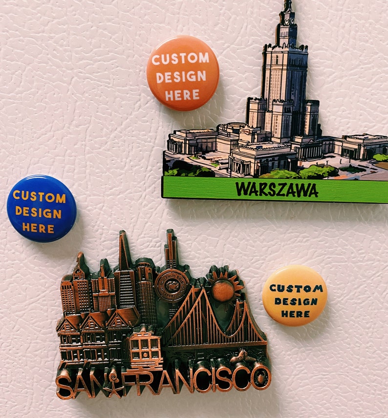 May include: Three refrigerator magnets featuring city skylines. The magnets are round and feature the text "Custom Design Here". The city skylines are of San Francisco, Warsaw, and an unidentified city.