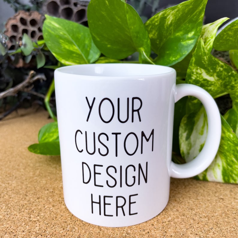 May include: White ceramic mug with a black inscription that reads "YOUR CUSTOM DESIGN HERE".