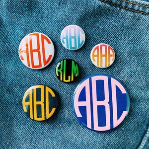 May include: Seven round buttons with different coloured backgrounds and white letters. The letters on the buttons spell out "ABC" and "KLM".