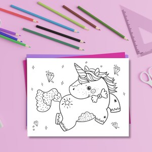May include: A black and white unicorn coloring page with diamond and star accents. Colored pencils in a white container, a pink triangle ruler, and white scissors are on a pink surface.