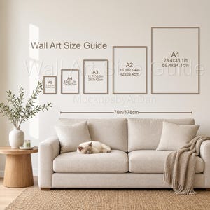 May include: A wall art size guide chart displaying A1, A2, A3, A4, and A5 frame dimensions in inches and centimeters. The chart is mounted above a beige sofa with a sleeping cat, a throw blanket, and a side table with a plant.