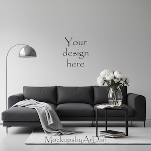 May include: A modern living room scene featuring a dark gray sofa with a light gray throw blanket. A small black side table holds a vase of white flowers and books. A silver arc lamp and a white rug complete the decor. Text on the wall reads "Your design here."