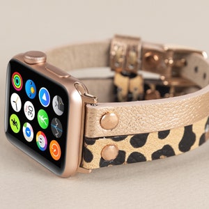Może przedstawiać: Złoty zegarek Apple Watch z czarno-złotym paskiem ze sk&oacute;ry w panterkę. Tarcza zegarka wyświetla r&oacute;żne ikony aplikacji.