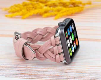 May include: A pink braided leather band for an Apple Watch. The band is made of woven leather straps and has a silver buckle.