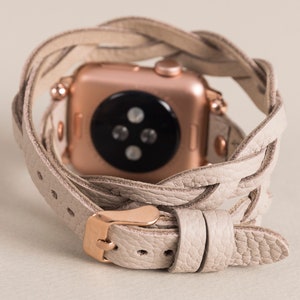 Op de afbeelding: Een beige leren horlogeband met een gevlochten ontwerp. De band is om een ​​rosegouden Apple Watch gewikkeld.