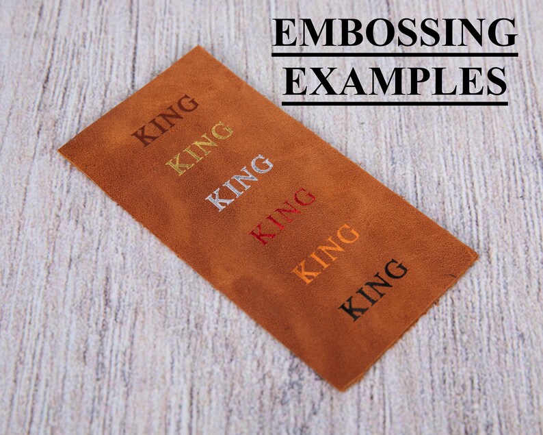 Pu&ograve; includere: Un pezzo rettangolare di pelle marrone con il testo EMBOSSING EXAMPLES in alto. Sotto, la parola KING &egrave; impressa sei volte in una colonna diagonale, visualizzata in diversi colori tra cui oro, argento, rosso, arancione e nero.