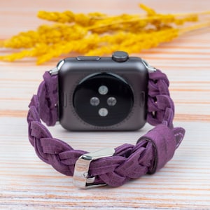Pu&ograve; includere: Un cinturino in pelle intrecciata viola per uno smartwatch. Il cinturino &egrave; intrecciato con un motivo intrecciato e ha una fibbia argentata.