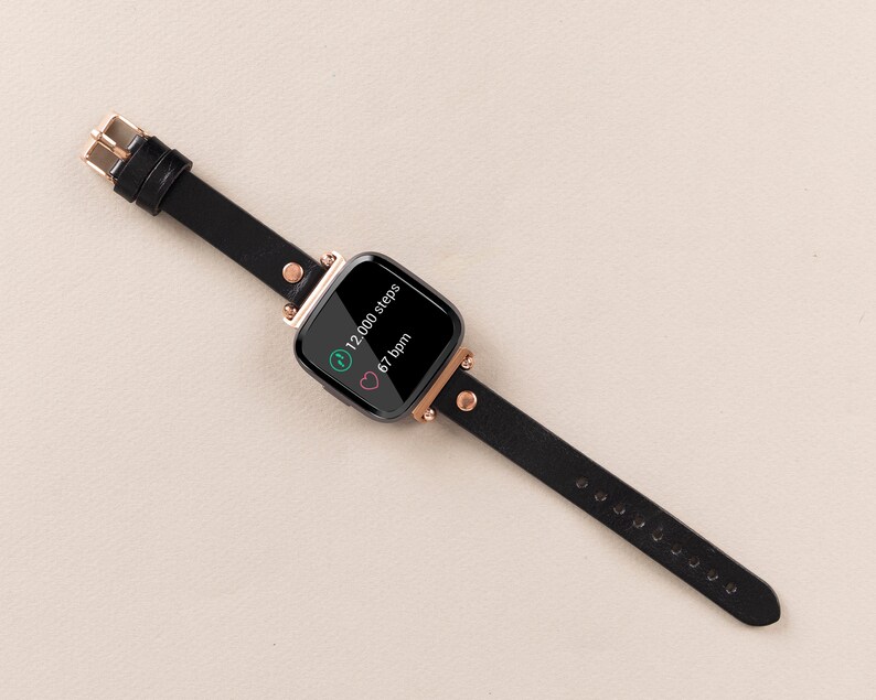 May include: Black fitness tracker with a rose gold band and a black screen displaying 12,000 steps and 67 bpm.