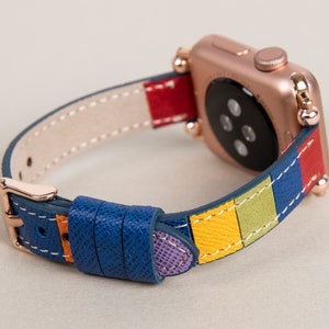 K&ouml;nnte beinhalten: Eine Apple Watch in Ros&eacute;gold mit einem bunten Lederarmband. Das Armband hat Streifen in Blau, Gelb, Gr&uuml;n, Rot und Lila.