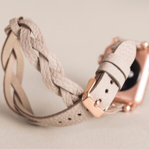 Op de afbeelding: Een lichtbeige gevlochten leren horlogebandje met een ros&eacute;gouden gesp en een bijpassend horloge.