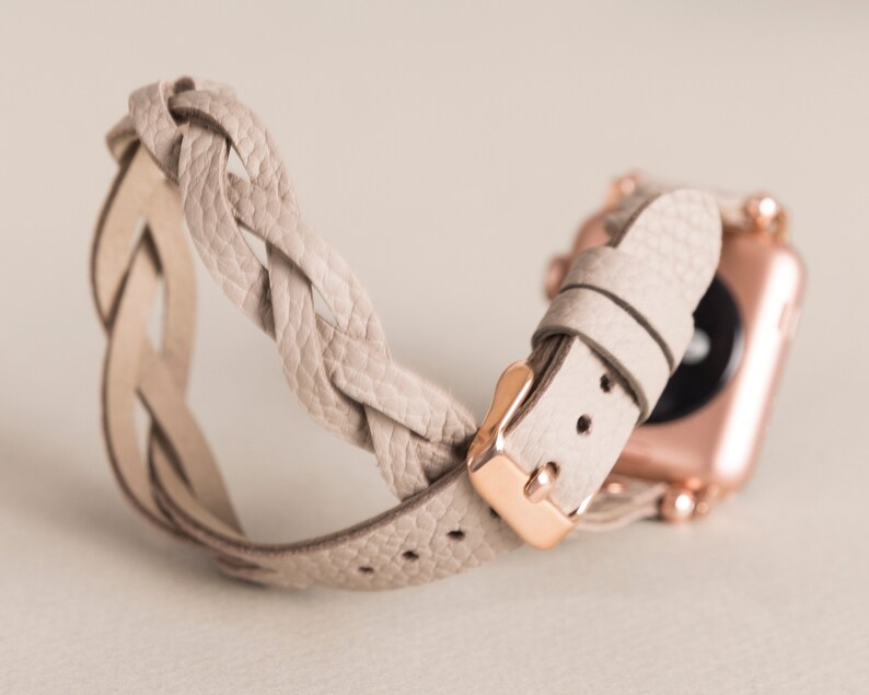 Op de afbeelding: Een lichtbeige gevlochten leren horlogebandje met een ros&eacute;gouden gesp en een bijpassend horloge.