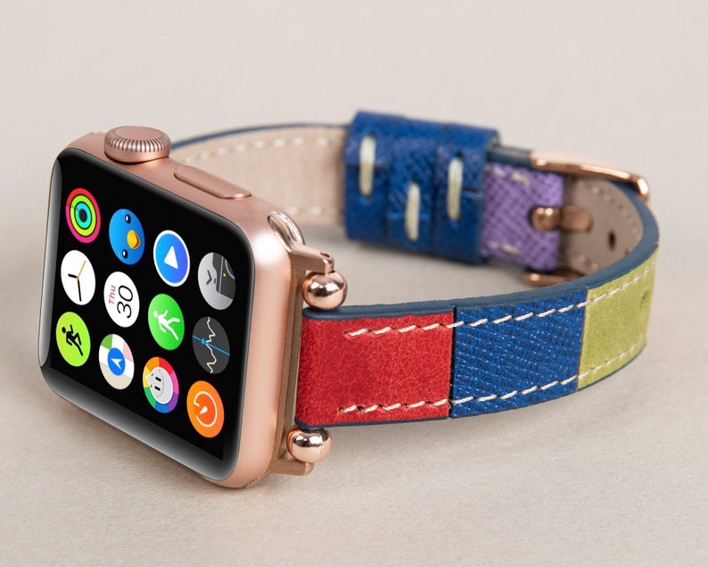 K&ouml;nnte beinhalten: Eine ros&eacute;goldene Apple Watch mit einem mehrfarbigen Lederarmband. Das Armband besteht aus rotem, blauem, gr&uuml;nem und violettem Leder. Das Zifferblatt der Uhr zeigt die Zeit, das Datum und mehrere App-Symbole.