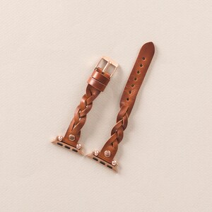 Puede incluir: Dos correas de reloj trenzadas de cuero marr&oacute;n con herrajes dorados. Las correas est&aacute;n dise&ntilde;adas para Apple Watches.