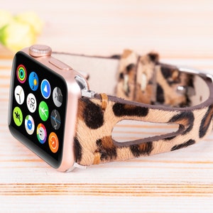 May include: A rose gold Apple Watch with a leopard print leather band. The watch face displays a variety of apps, including a clock, compass, and weather.