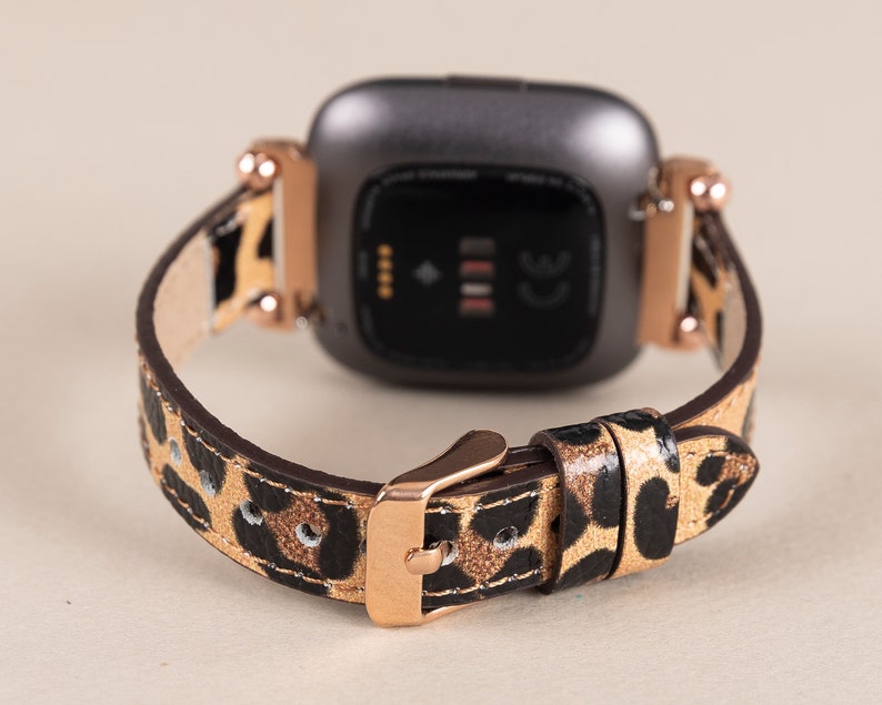 Puede incluir: Una correa de reloj de estampado de leopardo negro y dorado con una hebilla de oro rosa. La correa est&aacute; dise&ntilde;ada para un reloj inteligente con una cara cuadrada.