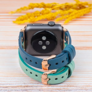 May include: A smartwatch with a black face and a blue and green leather band.