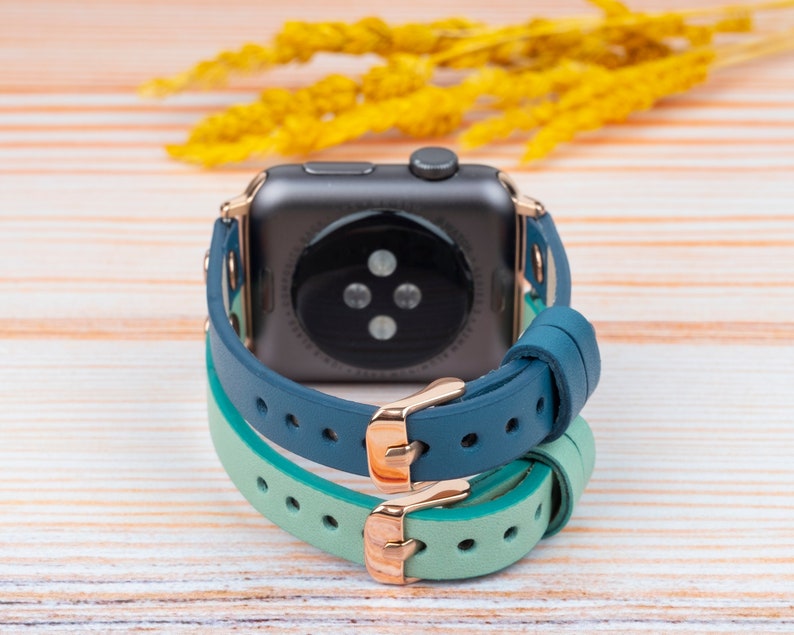 May include: A smartwatch with a black face and a blue and green leather band.