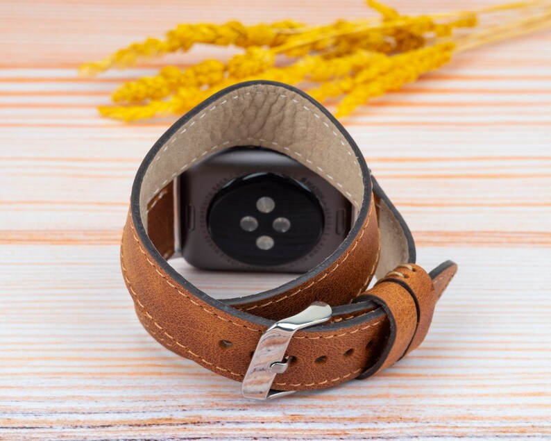 K&ouml;nnte beinhalten: Ein braunes Lederarmband mit einer silbernen Schlie&szlig;e. Das Armband ist f&uuml;r eine Smartwatch mit rundem Zifferblatt konzipiert.