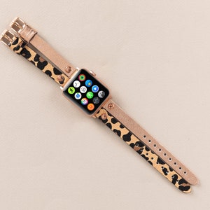 Może przedstawiać: Złoty pasek do Apple Watch z nadrukiem lamparta o podw&oacute;jnym pasku. Tarcza zegarka jest widoczna i pokazuje r&oacute;żne aplikacje.