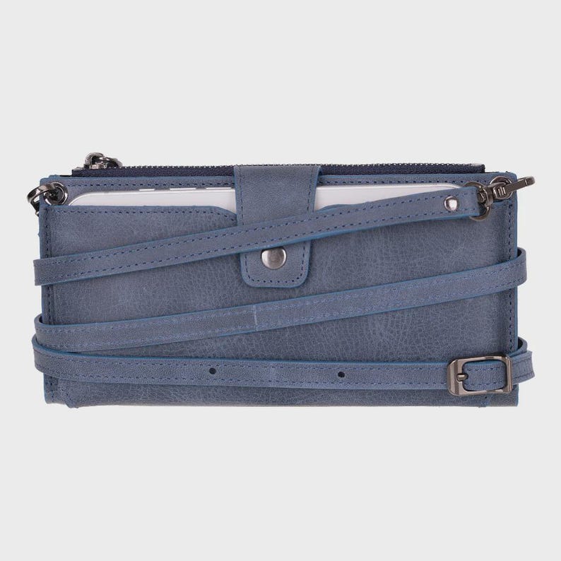 Pu&ograve; includere: Un portafoglio rettangolare color blu ardesia con finitura testurizzata, dotato di chiusura superiore con zip, patta centrale con bottone a pressione e un sottile cinturino regolabile avvolto attorno all'esterno. Include finiture in metallo scuro.