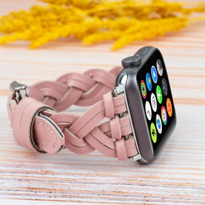 K&ouml;nnte beinhalten: Ein rosafarbenes geflochtenes Lederarmband f&uuml;r eine Apple Watch. Das Armband besteht aus geflochtenen Lederriemen und hat eine silberne Schnalle.