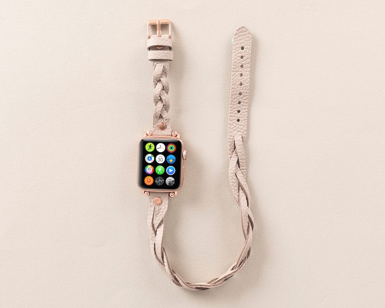Op de afbeelding: Een gevlochten leren horlogeband in een lichtbeige kleur met een ros&eacute;gouden gesp. De band is compatibel met Apple Watch.