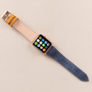 May include: A rose gold Apple Watch with a light pink leather strap and a dark blue leather strap.
