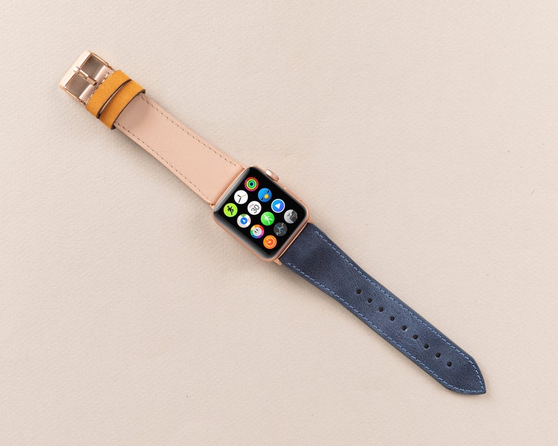May include: A rose gold Apple Watch with a light pink leather strap and a dark blue leather strap.