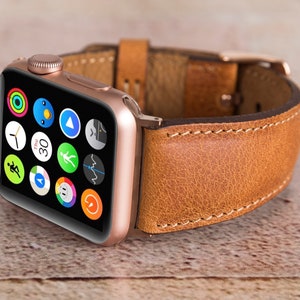 May include: A rose gold Apple Watch with a brown leather strap. The watch face shows a variety of app icons.