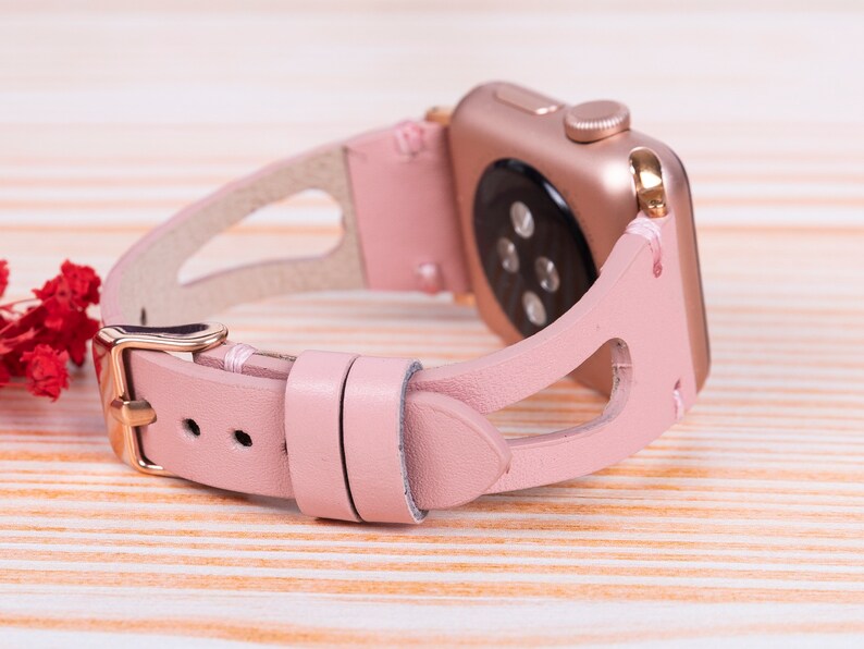 Peut inclure: Un bracelet de montre en cuir rose avec une boucle dor&eacute;e et un design d&eacute;coup&eacute;. Le bracelet est con&ccedil;u pour une montre intelligente.