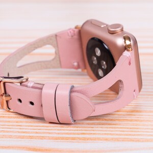 Peut inclure: Un bracelet de montre en cuir rose avec une boucle dor&eacute;e et un design d&eacute;coup&eacute;. Le bracelet est con&ccedil;u pour une montre intelligente.