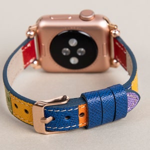 K&ouml;nnte beinhalten: Eine ros&eacute;goldene Apple Watch mit einem mehrfarbigen Lederarmband. Das Armband hat Streifen in Rot, Gelb, Gr&uuml;n, Blau und Lila.