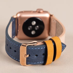 May include: A rose gold Apple Watch band with a blue leather strap and a yellow leather strap. The band is designed to fit a 40mm or 44mm Apple Watch.