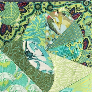 May include: A patchwork quilt block featuring a range of green and blue fabrics. The fabrics display various patterns, including floral, geometric, and abstract designs. The block is stitched together with white thread.