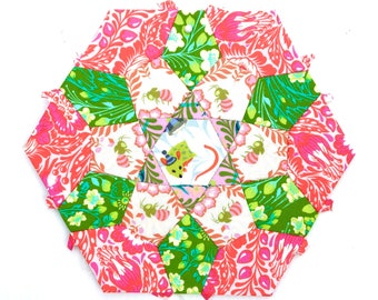 May include: A hexagonal quilt block with a starburst pattern in shades of pink, green, and white. The block is made up of smaller hexagonal pieces, each with a different floral print. The hashtag #hexieeasteriskquiltblock and the text @the_m_a_k_e_r are visible in the image.