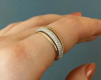 May include: Two gold rings with a pave diamond setting. The top ring has a twisted rope design.
