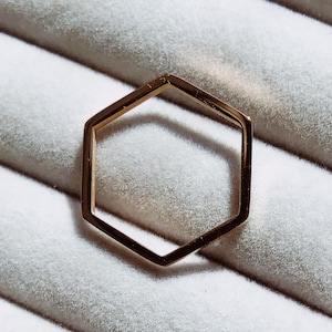 May include: A gold hexagonal ring with a smooth, polished finish.