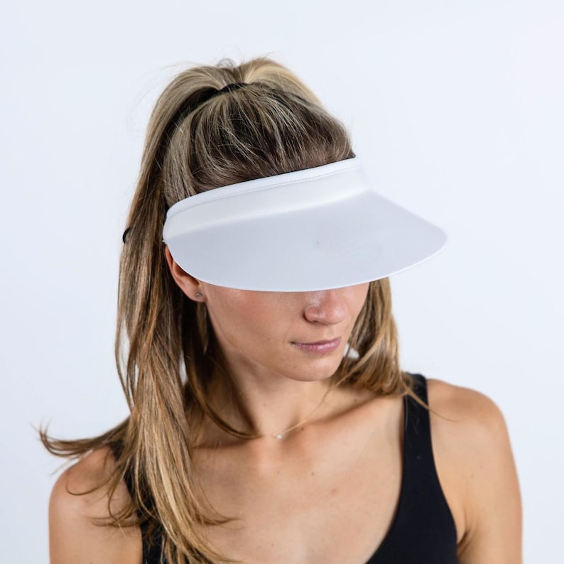May include: A white visor with a wide brim, worn by a person with long blonde hair.