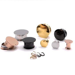 May include: Assortment of ear gauges in various sizes and colors, including silver, gold, black, and rose gold. The gauges are made of metal and have a smooth, polished finish.