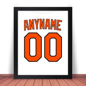 May include: A framed white jersey with the text "ANYNAME" and the number "00" in orange with black outlines.