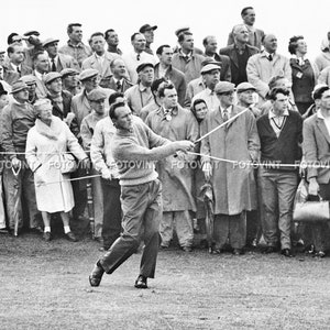 May include: A black and white photo of a man swinging a golf club. The man is wearing a sweater and pants. He is surrounded by a crowd of people watching him play golf.