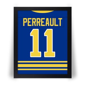 May include: Framed blue jersey with the name "PERREAULT" and the number "11" in yellow. The jersey has yellow stripes at the bottom and a yellow collar. The frame is black.
