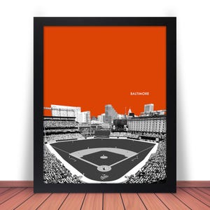 May include: A black and white illustration of a baseball stadium with the city skyline in the background. The stadium is filled with fans and the field is empty. The background is a bright orange color with the word "Baltimore" in white text.