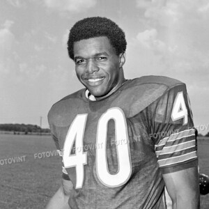 May include: A black and white photo of a football player wearing a jersey with the number 40 on it. He is smiling and looking at the camera.